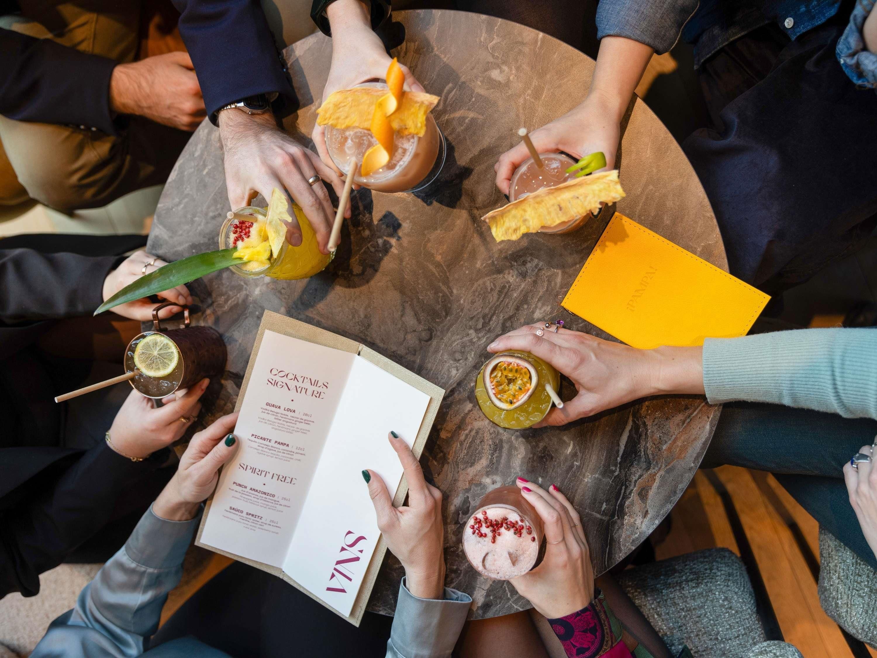A group of people holding drinks and a menu at a round table.
