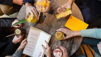 A group of people holding drinks and a menu at a round table.