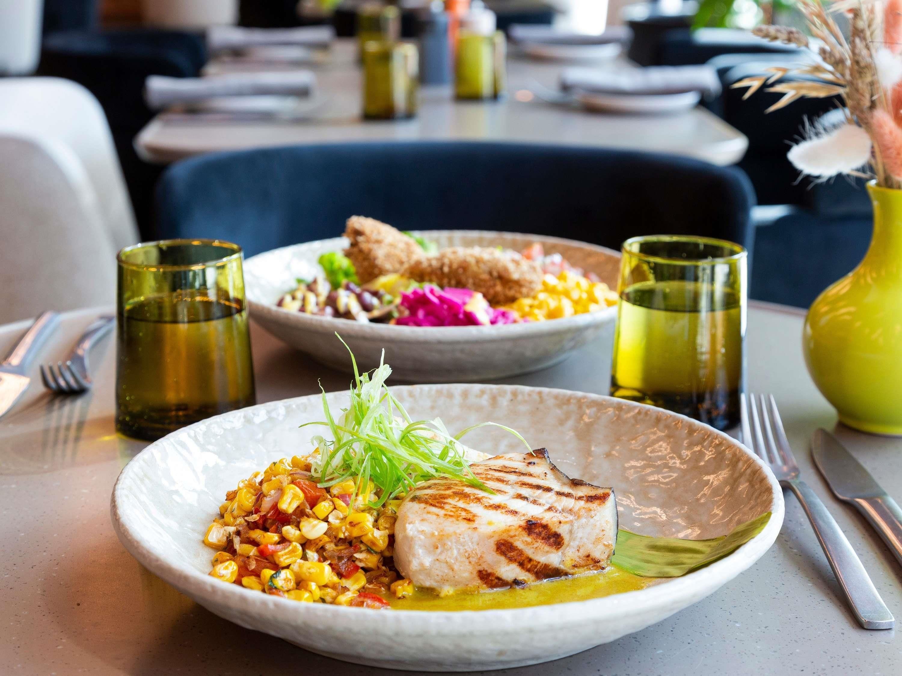 A dining table with plates of food, cutlery, and glasses.