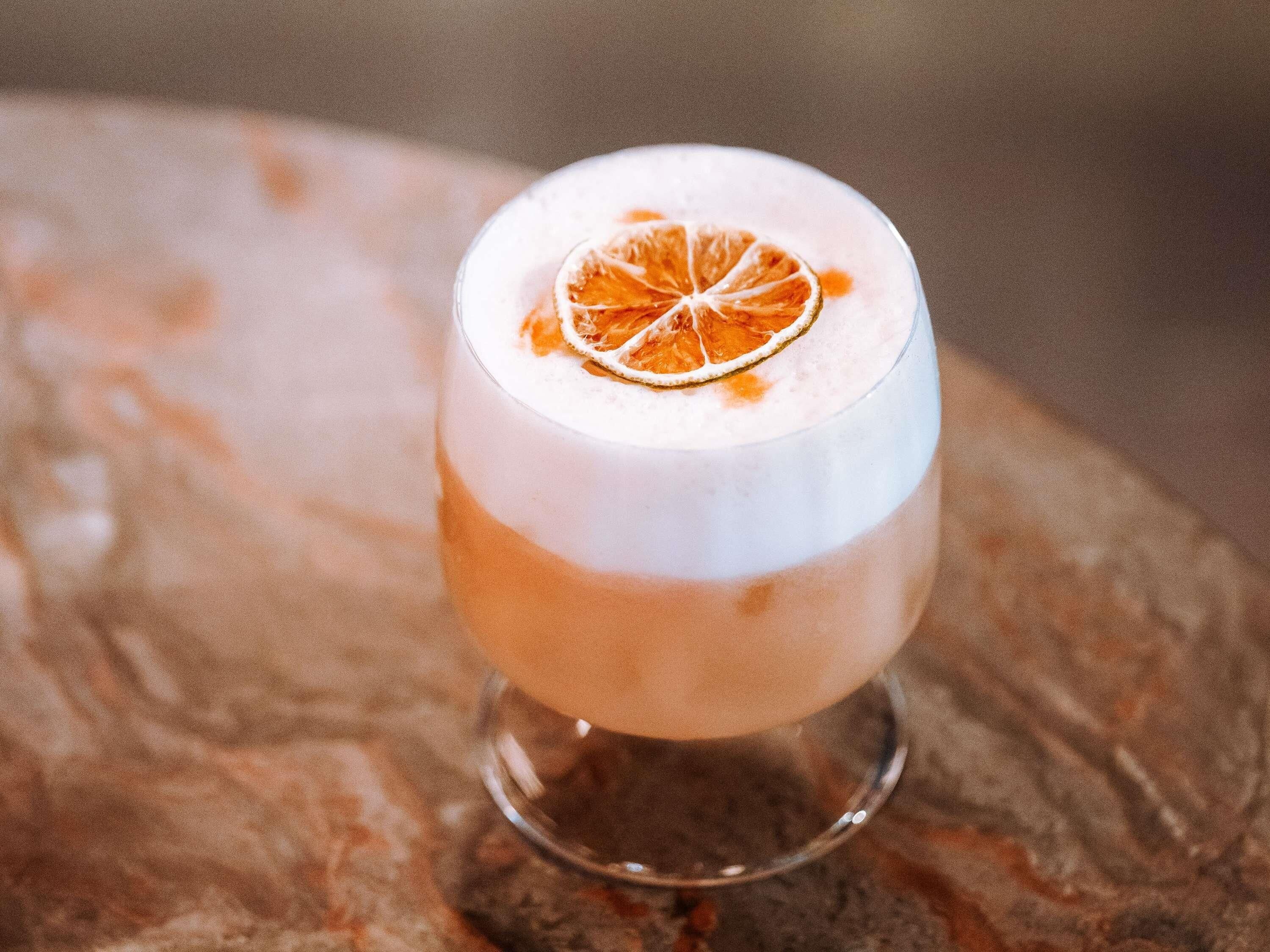 Un cóctel en un vaso con una rodaja de naranja encima.