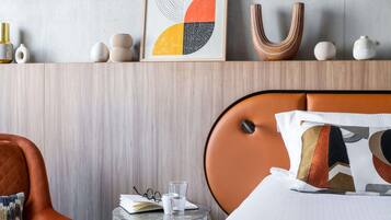 Habitación de hotel con una cama, una mesita redonda, una silla y un estante en la pared con adornos.