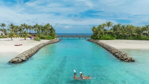 A clear turquoise waterway with a small boat in the middle, surrounded by white sandy beaches and palm trees. - SO/ Maldives (Emboodhoo)