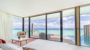 A modern hotel room with a large bed, a seating area with a view of the ocean, and a balcony with a pool. - SO/ Maldives (Emboodhoo)