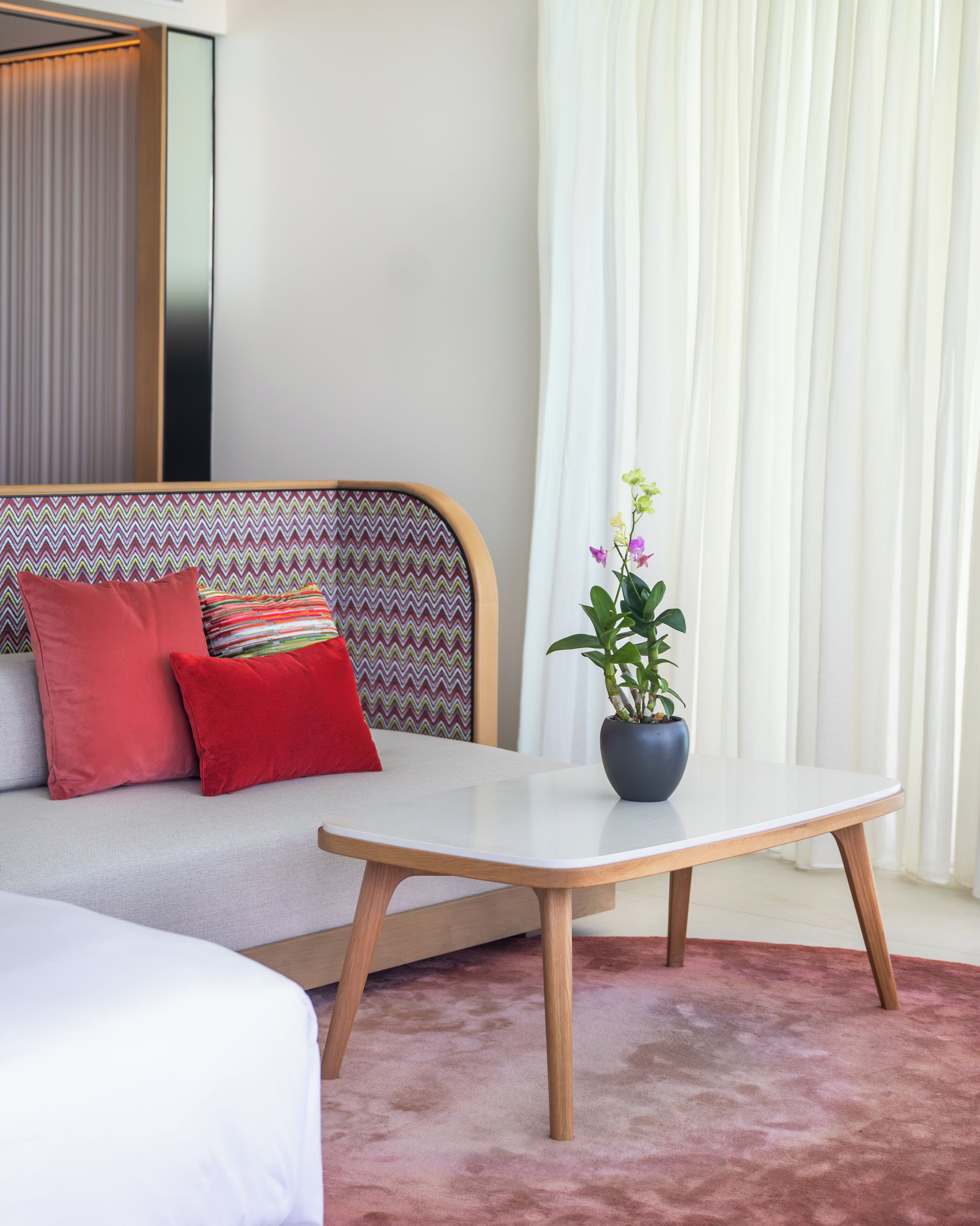 A modern hotel room with a sofa, a small table, and a potted plant.