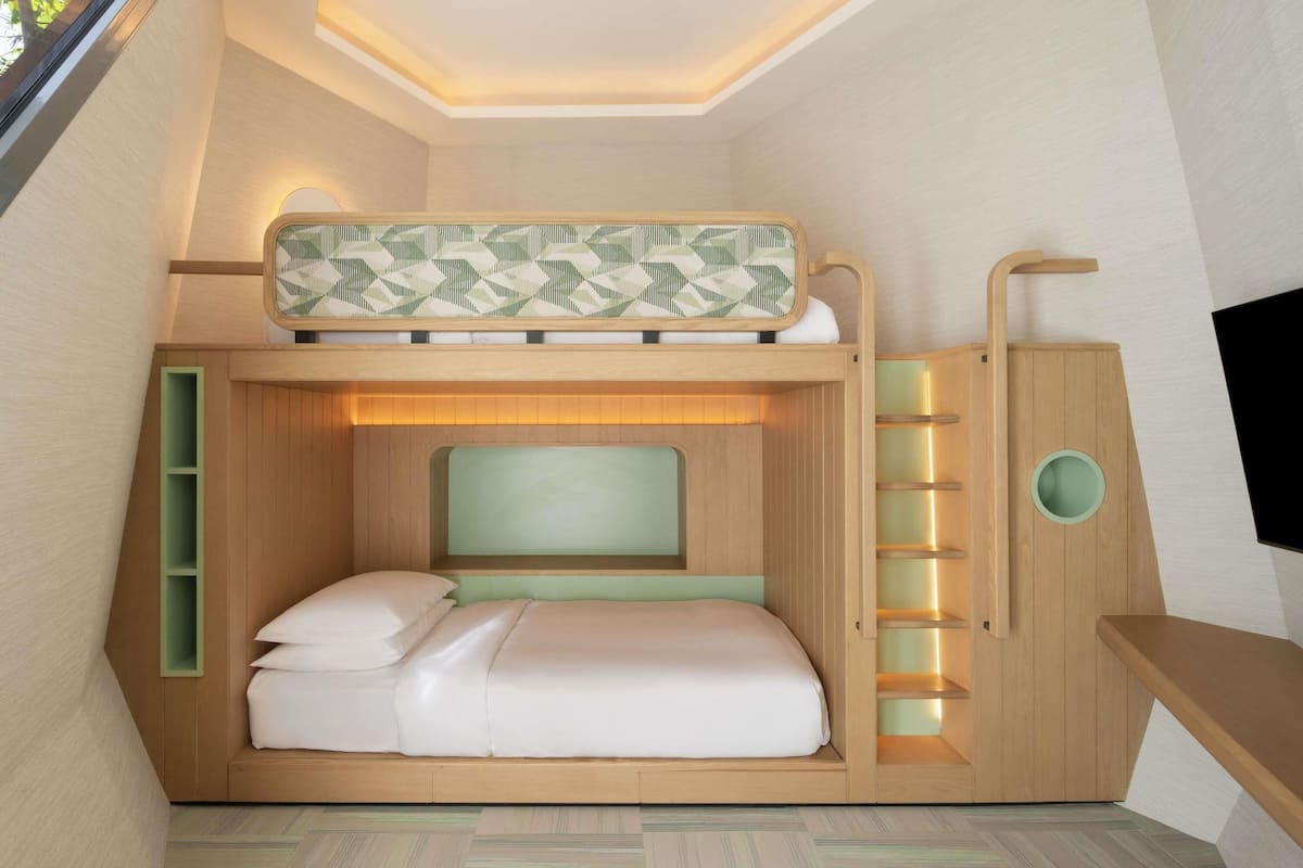 A bunk bed with a headboard, a bedside table, and a built-in shelf unit.