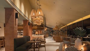 A spacious lobby with a high ceiling, wooden furniture, and a central seating area. - SO/ Maldives (Emboodhoo)