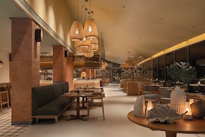 A spacious lobby with a high ceiling, wooden furniture, and a central seating area. - SO/ Maldives (Emboodhoo)