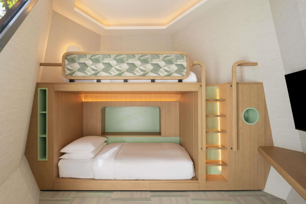 A bunk bed with a headboard, a bedside table, and a built-in shelf unit.
