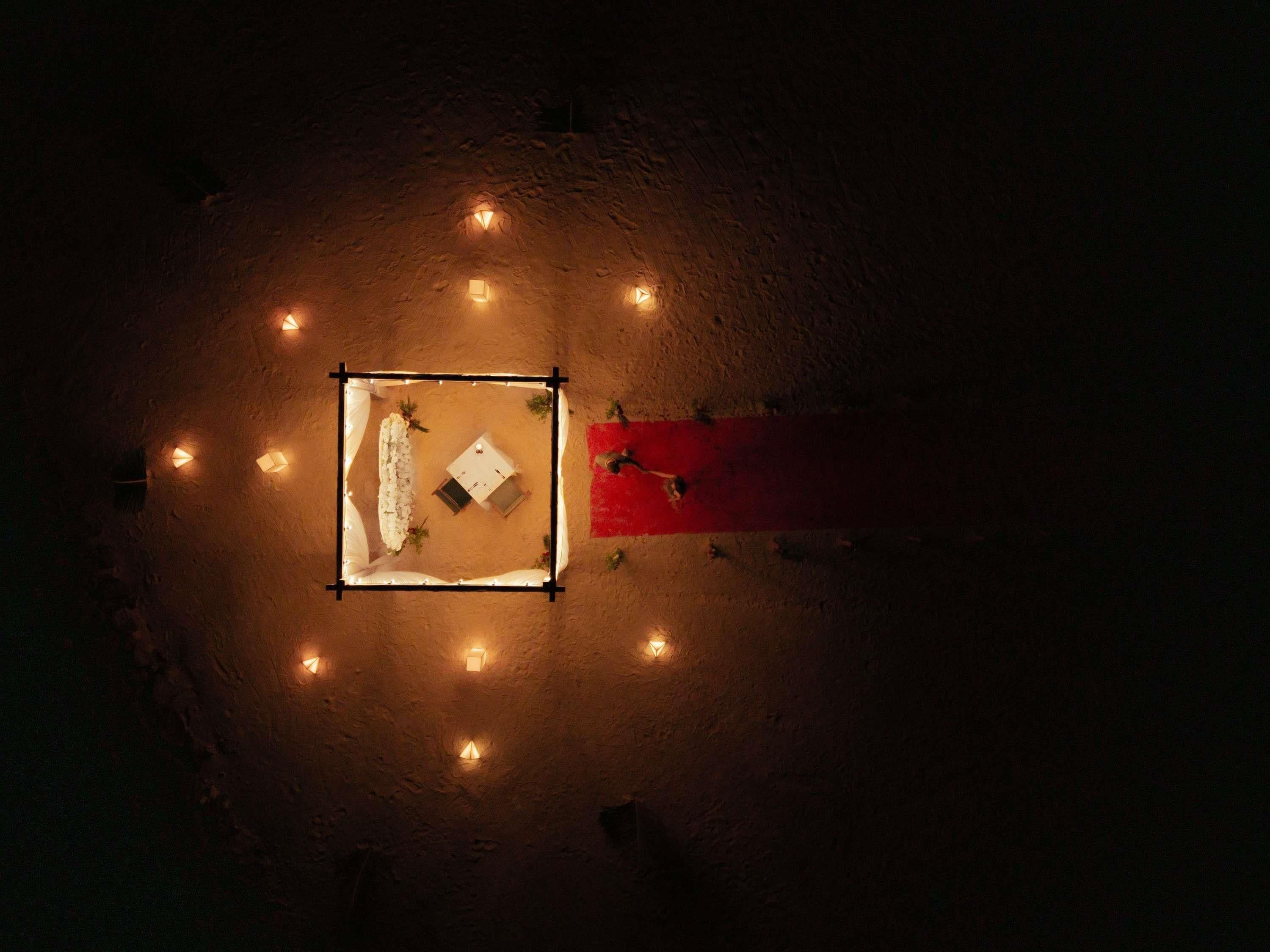 Una habitación circular con una mesa central y cuatro sillas, rodeada de luces distribuidas uniformemente.