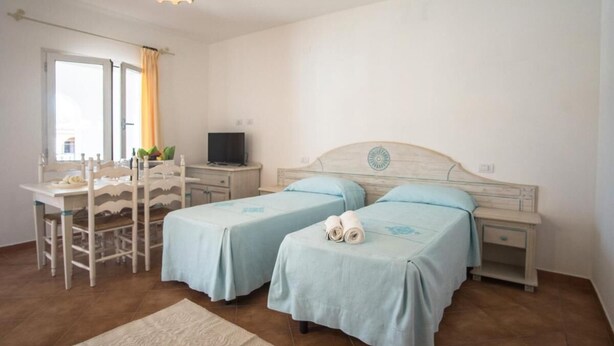 A bedroom with two beds, a desk, a chair, a TV, and a window with curtains. - Superb Residenze del Golfo di Orosei No2196 (Orosei)