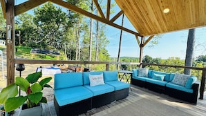 Un espace extérieur aménagé avec des meubles de jardin, comprenant des canapés bleus avec des coussins et un tapis à motifs chevrons.