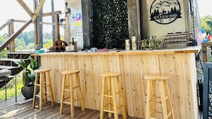 Un comptoir en bois avec des tabourets, un gril en métal et un logo sur le mur.