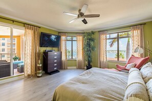 A bedroom with a bed, a ceiling fan, a TV, and a view of the outside. - 5th Floor Luxury Condo with Gulf Views and Steps from the Beach (Clearwater)
