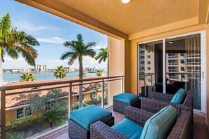 A balcony with wicker furniture and a view of the marina. - 5th Floor Luxury Condo with Gulf Views and Steps from the Beach (Clearwater)