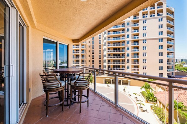 Enjoy a peaceful moment on this balcony with a table and chairs, taking in the views of the surrounding high-rise building.