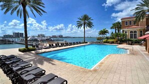 Ein Pool mit Liegestühlen, Palmen und Blick auf eine Marina.