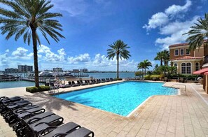 Relax by the pool overlooking the marina and body of water, surrounded by palm trees and Mediterranean-style architecture.