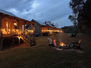 Ein rustikales Holzhaus mit Veranda und Treppe, einem Feuerkorb und Sitzgelegenheiten im Freien.
