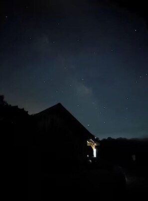 Un ciel nocturne étoilé au-dessus d’une silhouette sombre d’un bâtiment.