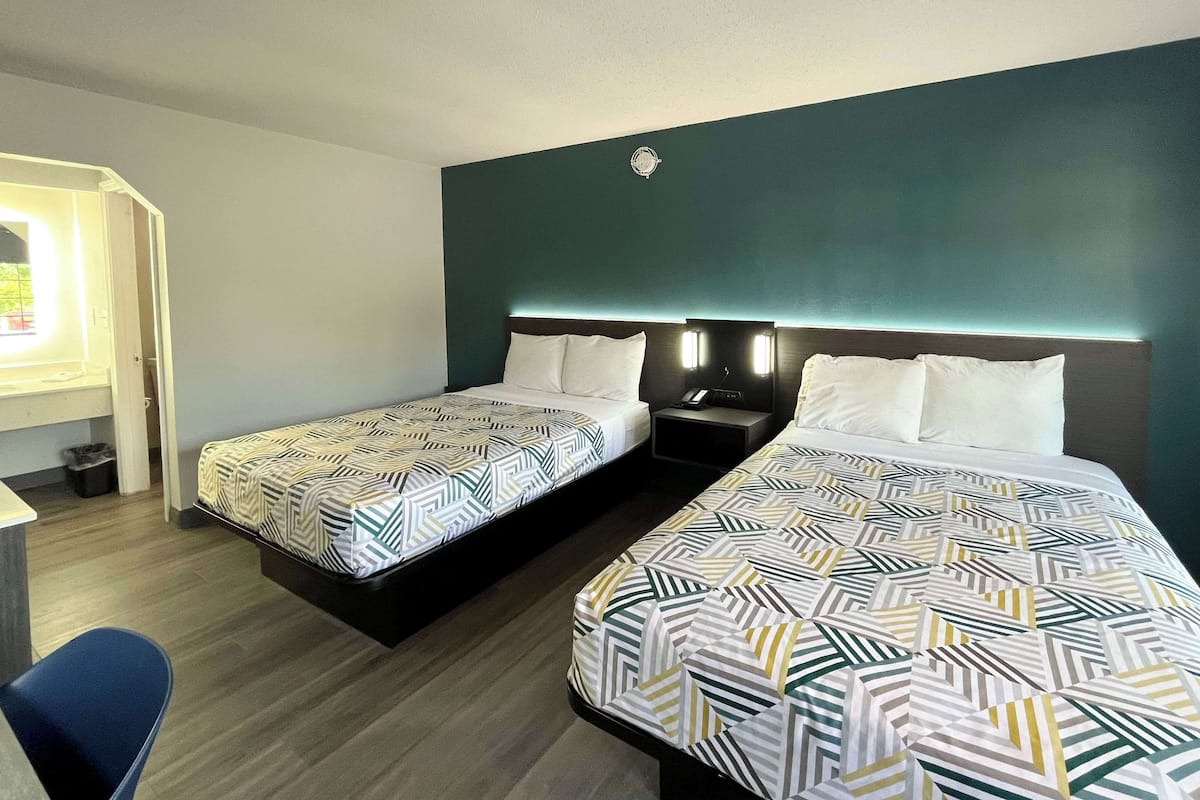 A hotel room with two beds, a desk, and a chair.