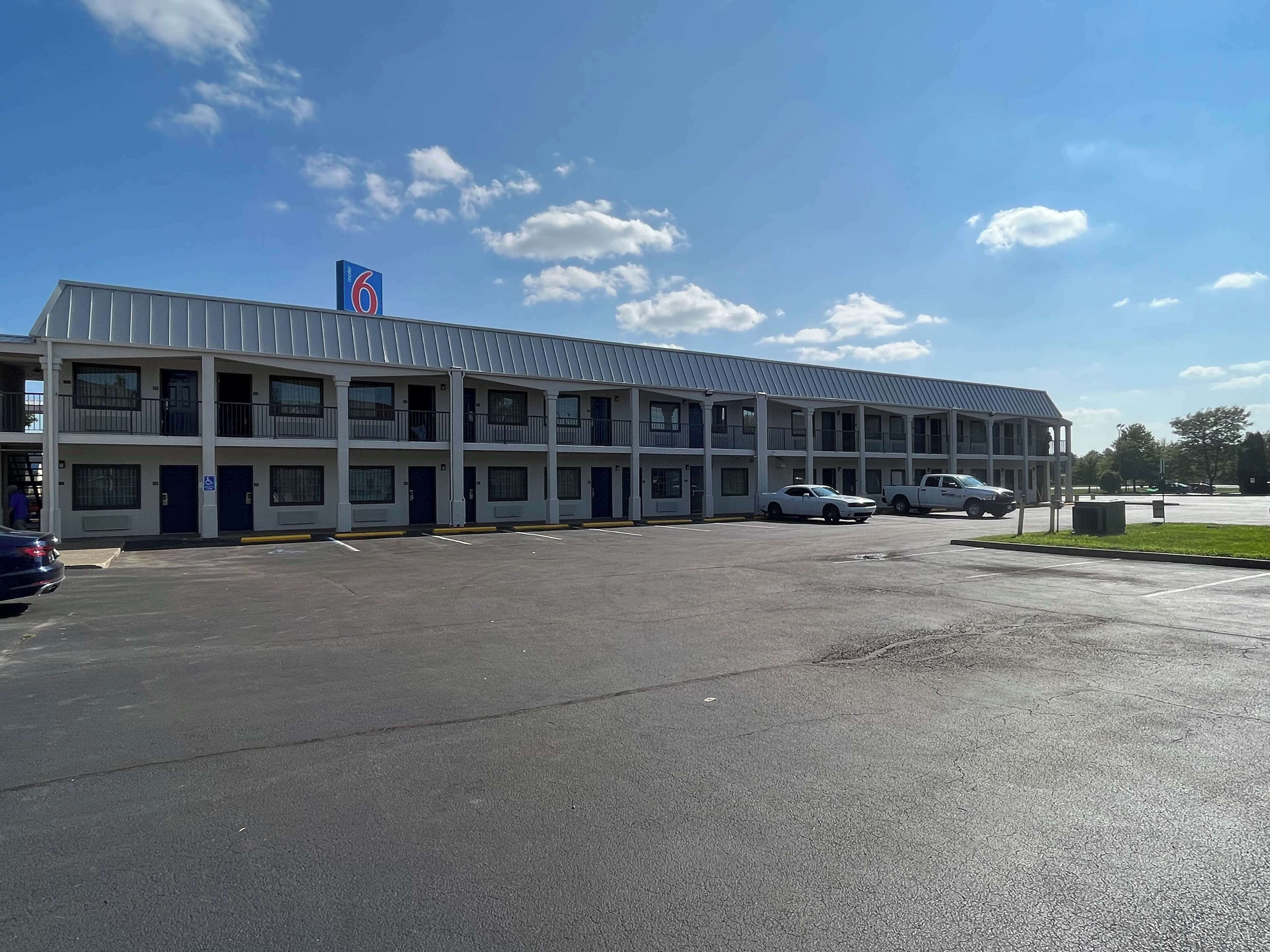 A multi-story motel with a parking lot and several cars parked.