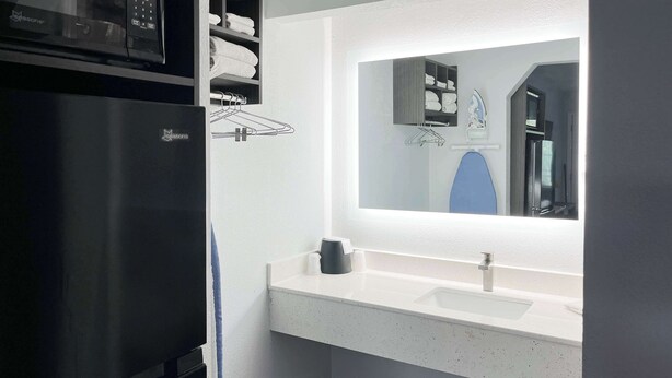 A modern bathroom with a built-in microwave, a sink with a mirror, and a towel rack. - Studio 6 Suites - Lafayette, IN (Lafayette)