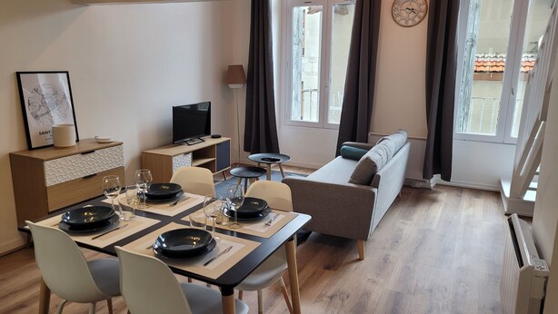 Ein modernes Wohnzimmer mit Essbereich, einer Couch, einem Fernseher und einer Wanduhr.