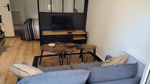 A cozy living area with a sofa, a coffee table, and a TV stand. - Studio cosy Saint-Étienne centre (Saint-Ã‰tienne)