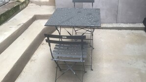 A metal outdoor table and bench set against a concrete wall. - Studio cosy Saint-Étienne centre (Saint-Ã‰tienne)