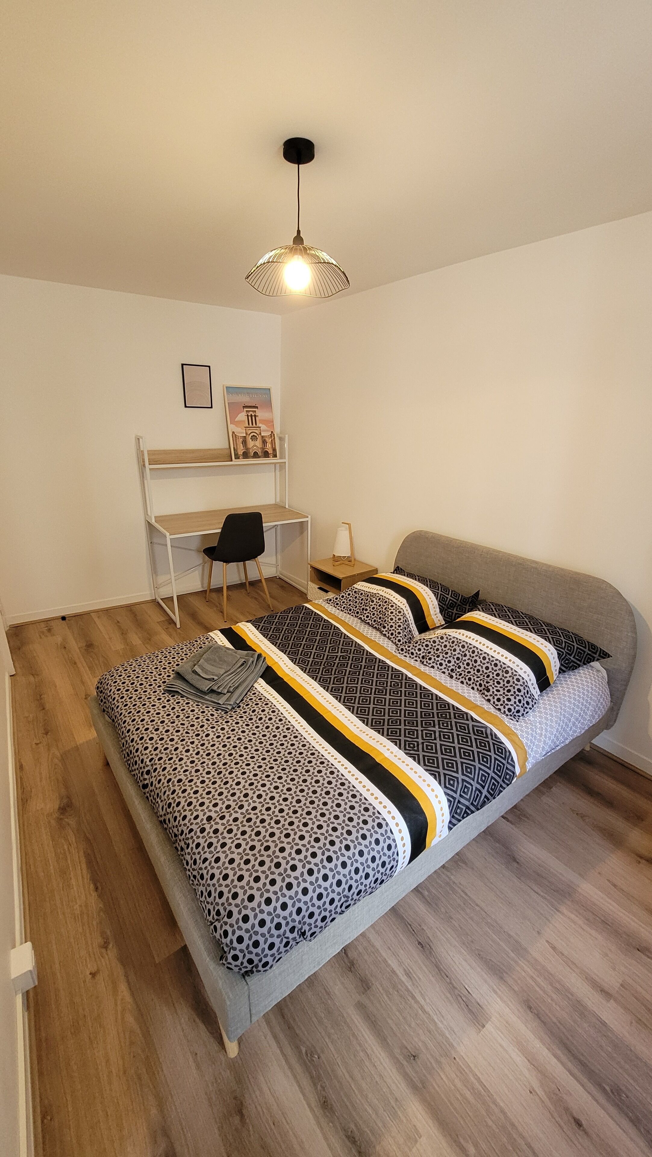 A bedroom with a bed, a desk, and a chair.