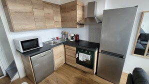 Una cocina compacta equipada con microondas, fregadero, cocina y refrigerador.