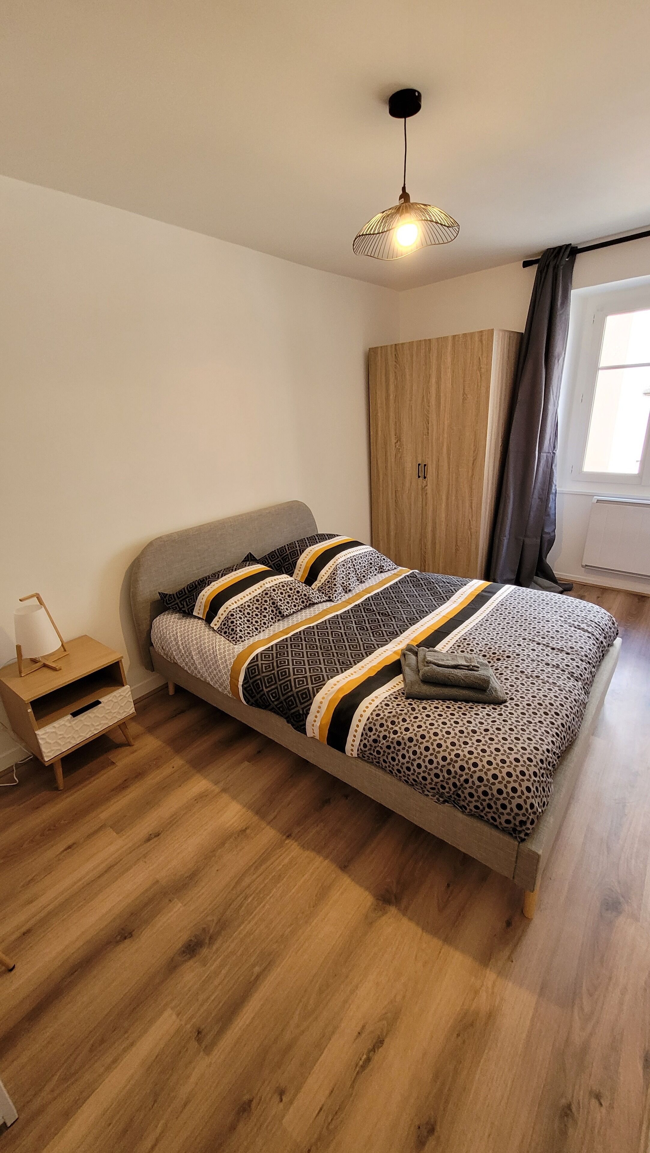 Une chambre à coucher avec un lit, une table de chevet, une armoire et une fenêtre.