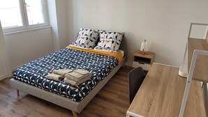 Un dormitorio moderno con cama, mesita de noche y escritorio.