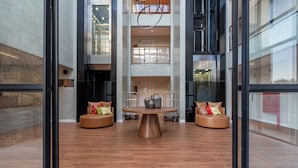 Eine moderne Lobby mit einem runden Tisch in der Mitte, zwei Ledersofas und einem Glastürbereich.