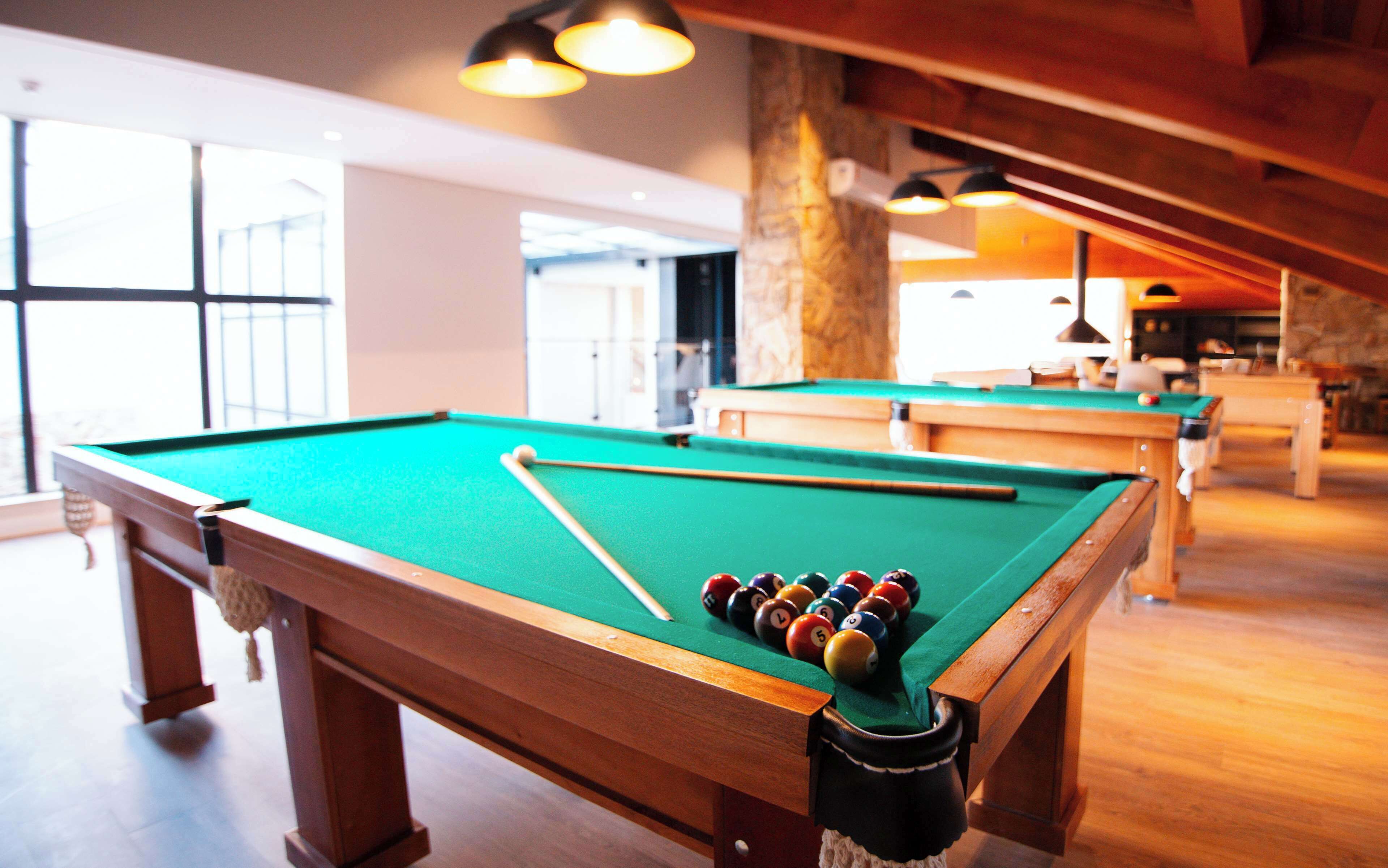 A pool table with balls, a cue stick, and a pool table cloth.