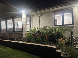 A residential building with a brick exterior, large windows, and a garden with flowering plants. - 🐎 2 Miles to Flintfields, Fenced Yard pet friendly, FREE RENTAL Golf Cart (Williamsburg)
