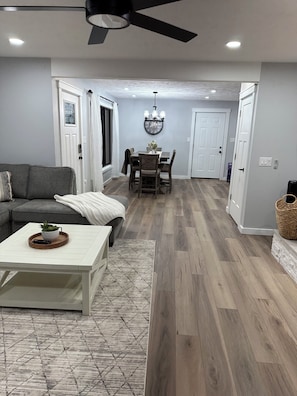 A modern living room with a grey sofa, a white coffee table, and a patterned rug.