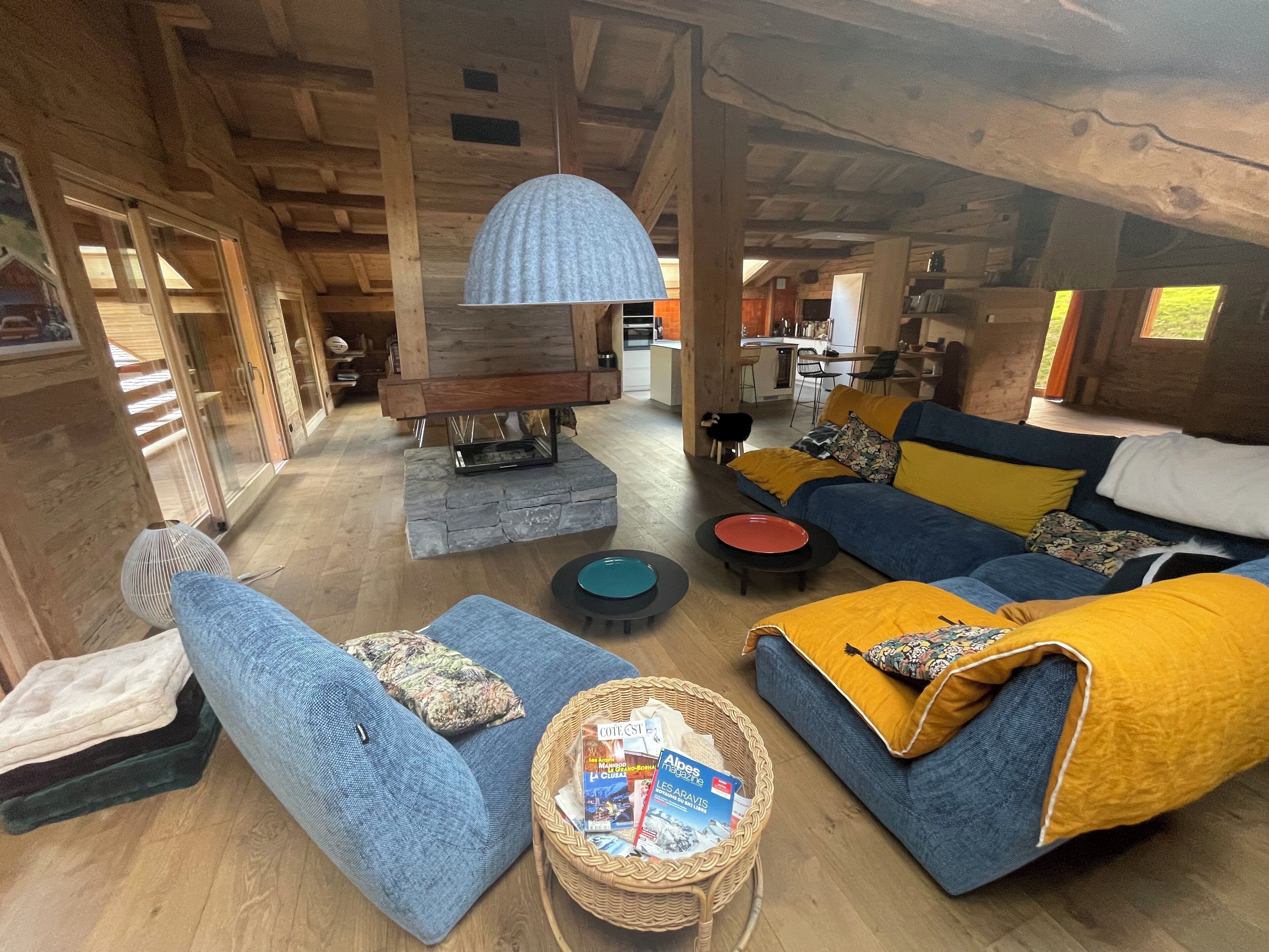 A cozy living room with a blue sofa, a yellow throw blanket, and a wicker basket with magazines.