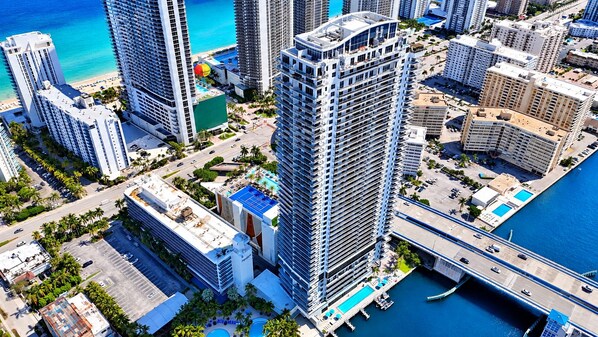 A high-rise hotel with multiple balconies, a swimming pool, and a view of the ocean. - This impressive 2-bedroom corner apartment combines elegance, comfort, and breathtaking views (Hollywood)