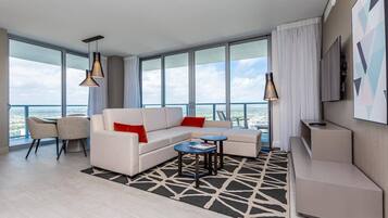 Une chambre d’hôtel moderne dotée d’une grande fenêtre, d’un canapé, d’une table basse et d’un téléviseur.