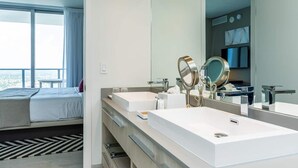 A modern hotel room with a large bed, a double sink, and a large mirror. - This impressive 2-bedroom corner apartment combines elegance, comfort, and breathtaking views (Hollywood)