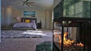 Un dormitori amb un llit, un ventilador de sostre, un quadre i una llar de foc.