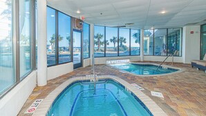An indoor swimming pool with clear views of palm trees and a beach through large windows. - NEW! Palace Resort TRUE Oceanfront STUDIO Condo (Myrtle Beach)