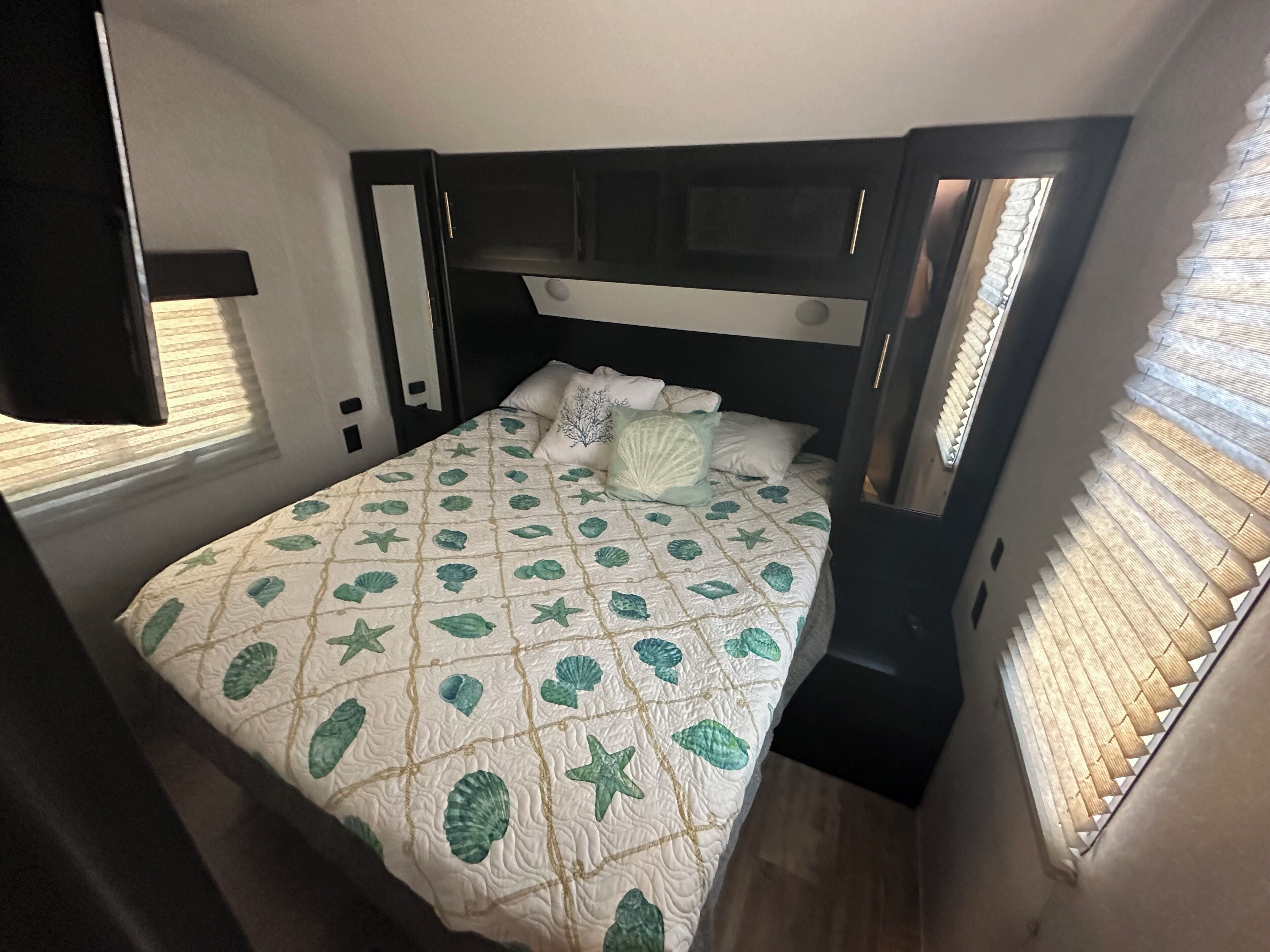Habitació compacte amb un llit, una tauleta de nit i una finestra amb persianes.
