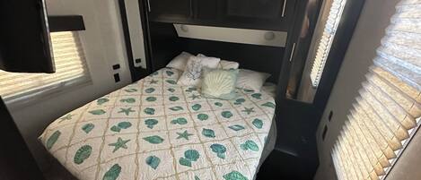 Habitació compacte amb un llit, una tauleta de nit i una finestra amb persianes.