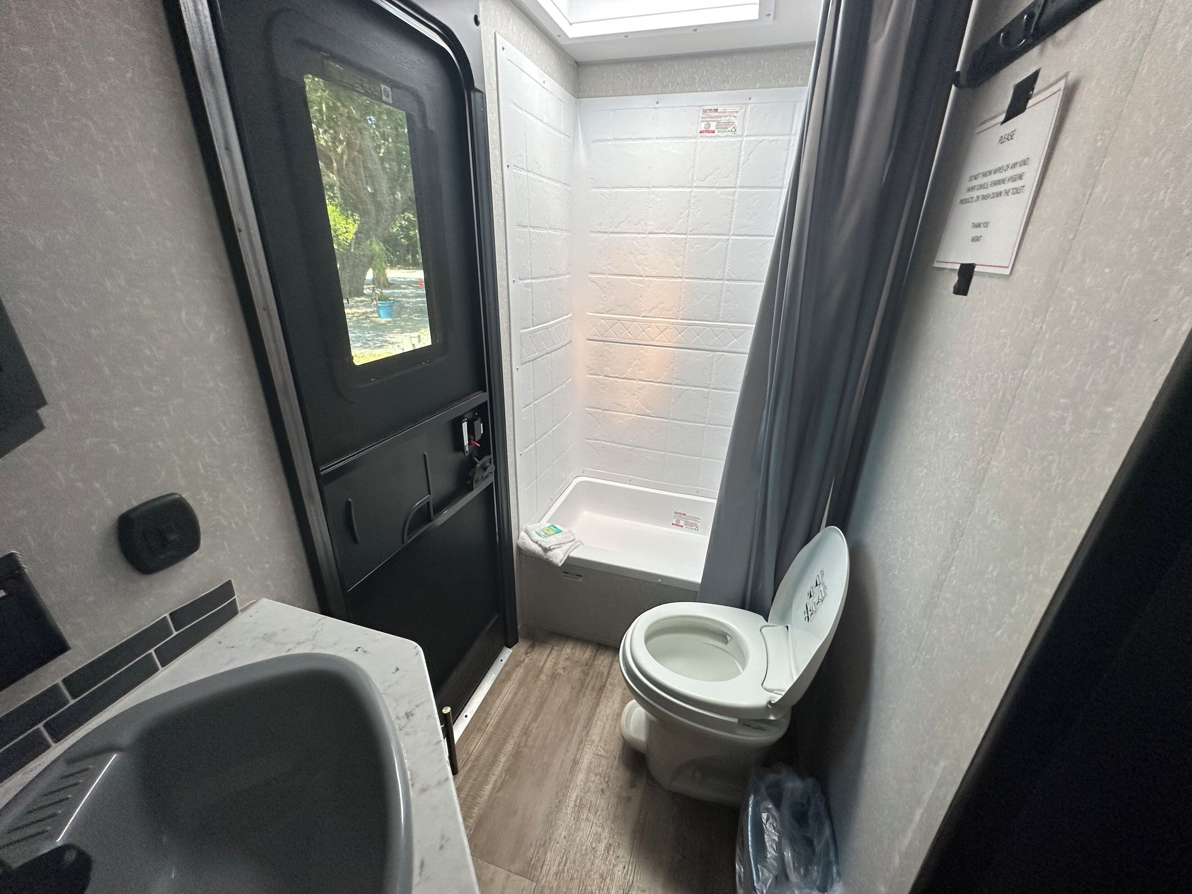 A compact bathroom with a toilet, sink, and shower.