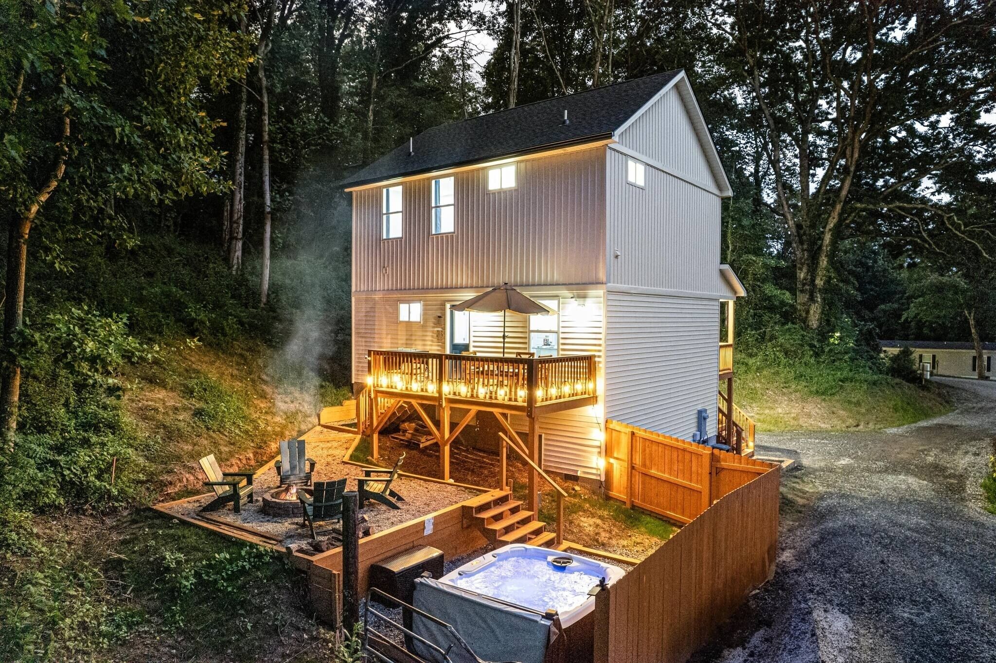 A two-story house with a deck, outdoor hot tub, and a fire pit.