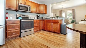 A kitchen with wooden cabinets, stainless steel appliances, and a wooden floor. - Charming Park Circle Bungalow with Screened Porch (North Charleston)