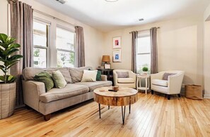 A living room with a sofa, armchairs, a coffee table, and a potted plant.