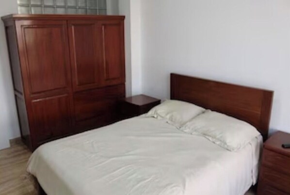Cozy retreat with a single bed, wooden headboard, and a wardrobe for your belongings.